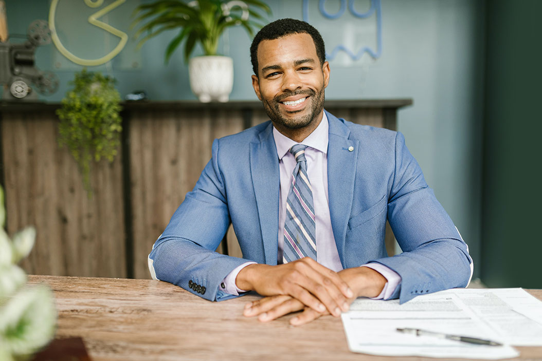 professional looking mortgage broker in a suit, with a document on a wood desk