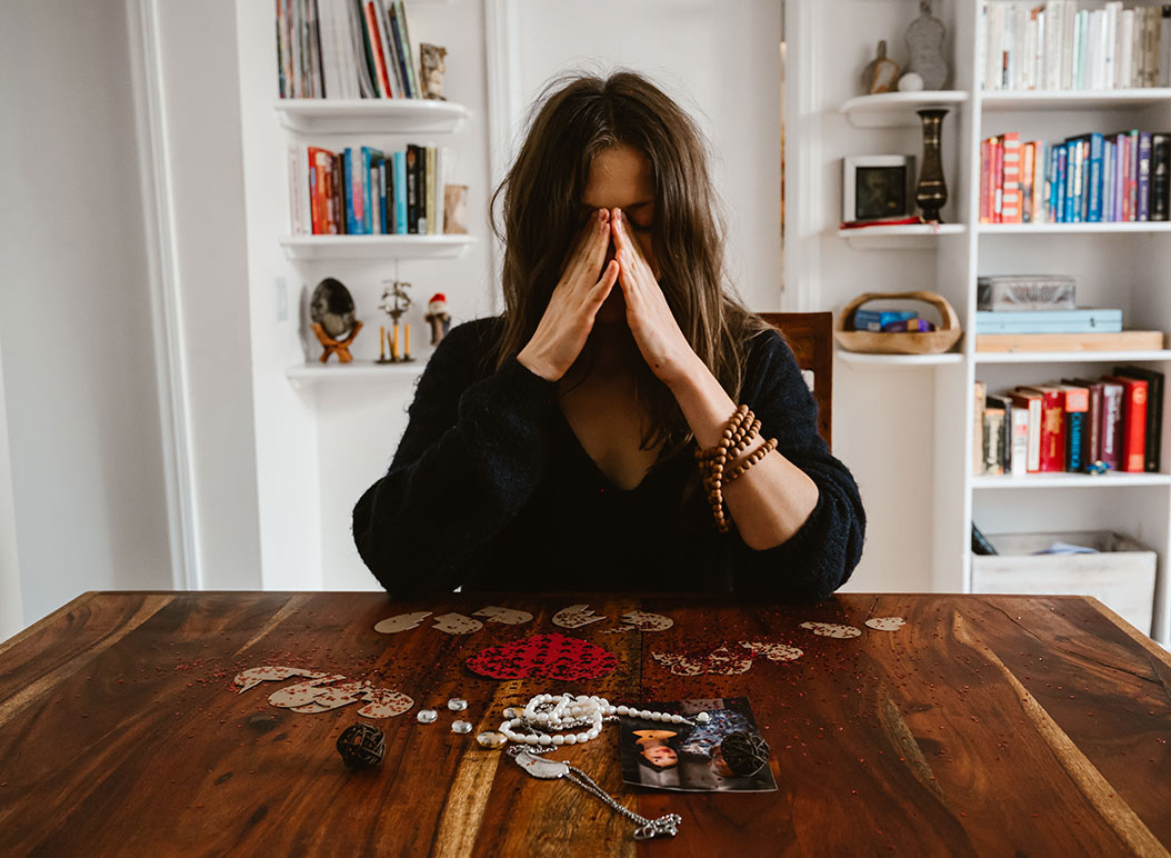 Woman with hands in front of face, sad at home