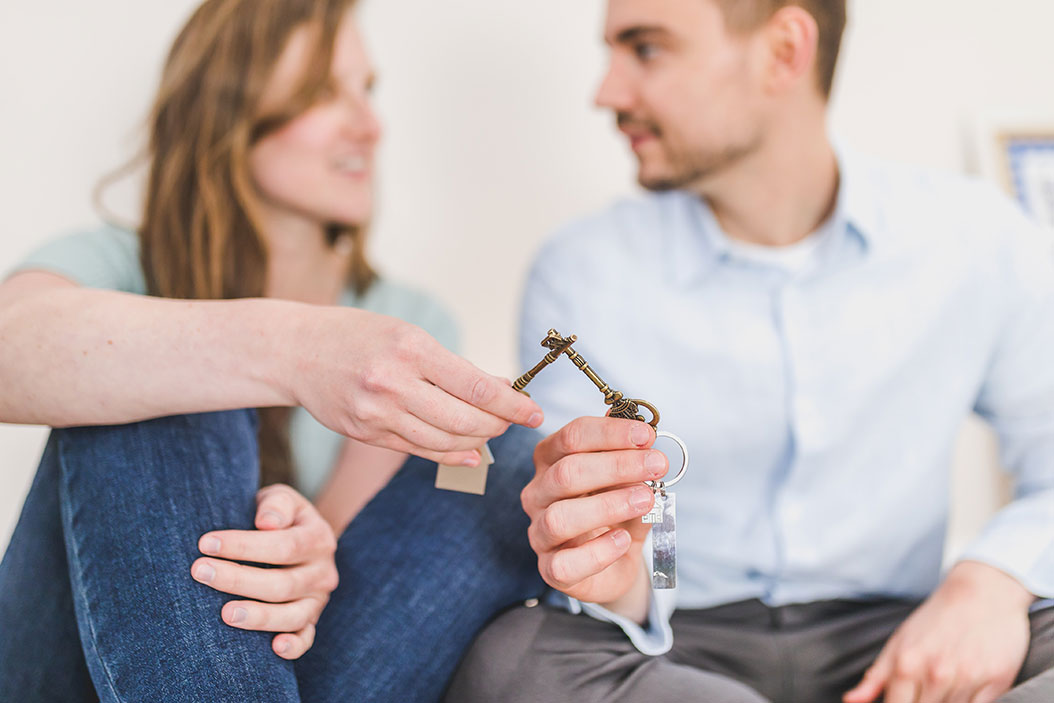 an out of focus couple holding house keys, touching